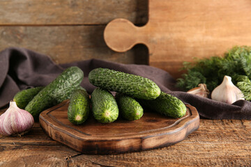 Board with fresh cucumbers and garlic on wooden background
