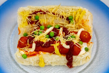 Traditional Brazilian style hot dog with sausage, peas and straw potatoes