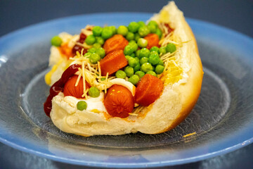 Traditional Brazilian style hot dog with sausage, peas and straw potatoes