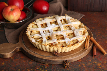 Wooden board of delicious apple pie with cinnamon and star anise on dark table