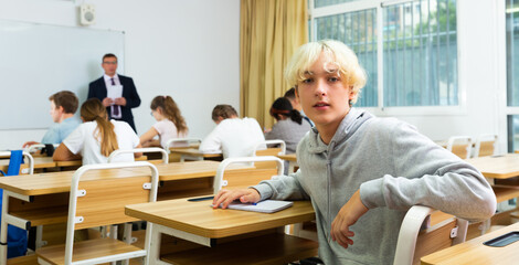 Fototapeta premium Young teenager is sitting at the desk in the classroom