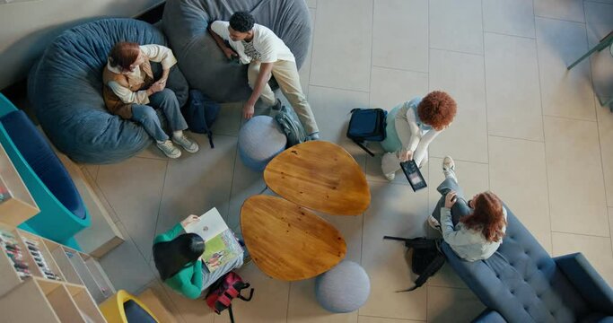 Above, university student and study or relax at library on campus for education, academics and knowledge. People, college and learner with conversation for exam, test and group assignment as friends