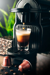 Coffee capsule machine preparing coffee in a glass. Mockup place for your text