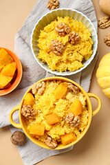 Pot and bowl of tasty millet porridge with pumpkin on orange background