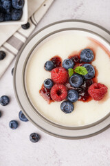 Bowl of tasty semolina porridge with fresh berries on white background