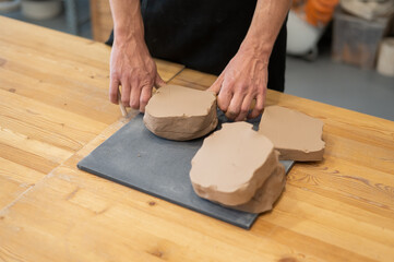 A potter cuts a piece of clay into pieces before using it in the workshop. 