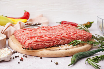 Wooden board of fresh minced meat with spices on white background