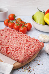 Wooden board of fresh minced meat with spices on white background