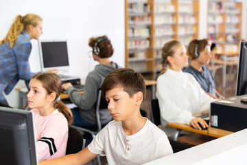 Obraz premium Portrait of a ten-year-old schoolboy studying at a computer in the classroom at a informatics lesson with classmates