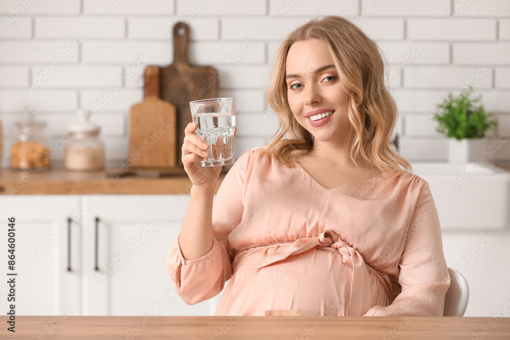 Poster Young pregnant woman with glass of water in kitchen