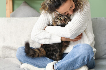 Happy mature woman with cute cat sitting on sofa at home © Pixel-Shot