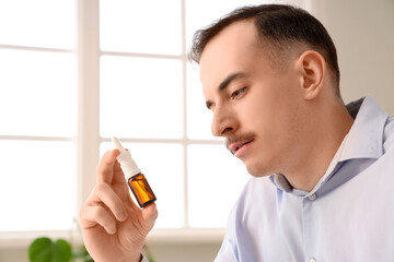 Ill businessman with nasal drops in office, closeup