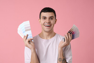 Young man with paint palettes on pink background
