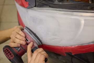 Obraz premium Person using a machine to polish automotive lighting on a car headlight