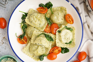 Bowl of tasty ravioli with vegetables on grey background