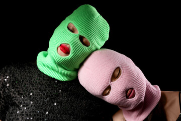 Beautiful young stylish women in balaclavas on black background