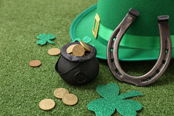 Pot with golden coins, horseshoe and leprechaun hat on grass. St. Patrick's Day celebration