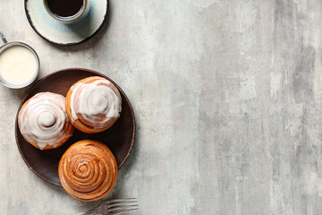 Plate with cinnamon buns, cream and cup of coffee on grey grunge background