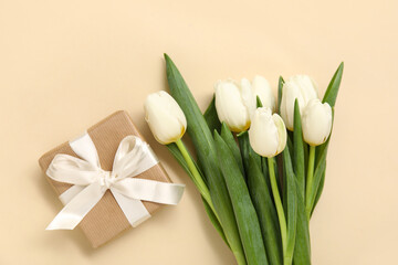Gift box with white tulips on beige background