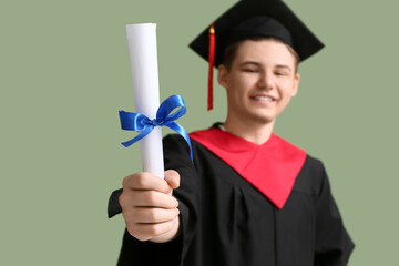 Happy male graduate with diploma on green background