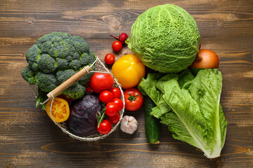 Basket with different fresh vegetables on wooden background