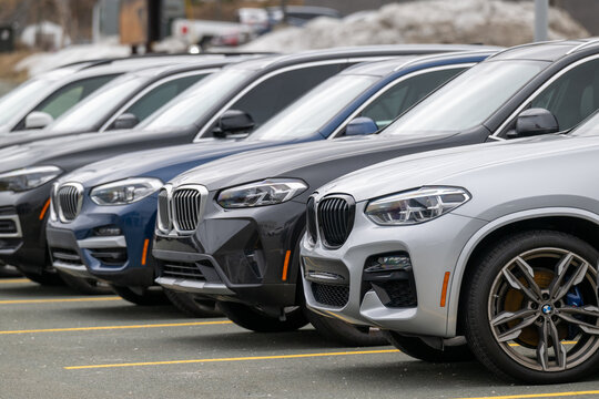 St. John's, Newfoundland - July 6, 2024: A row of blue and grey BMW i7 EUV utility vehicles on the parking lot of a car dealership. The new vehicles are electric rechargeable automobiles with plugs.