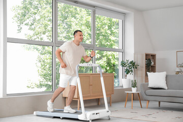 Sporty young man training on treadmill at home
