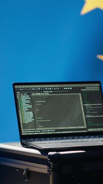 Vertical video Laptop in European Union command center used by counterterrorism department to run security protocols against propaganda bots trying to destabilize democracy, isolated over EU flag