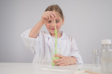 Caucasian girl doing chemical experiments on a white background. Making slime.