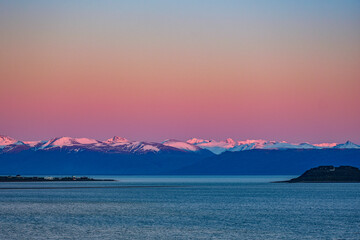 Amanecer sobre montañas nevadas detrás de un lago