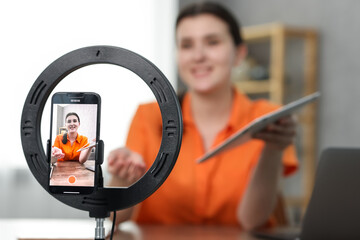 Technology blogger explaining something while recording video at home, focus on smartphone