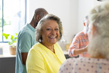 Smiling senior woman enjoying time with friends in cozy home gathering