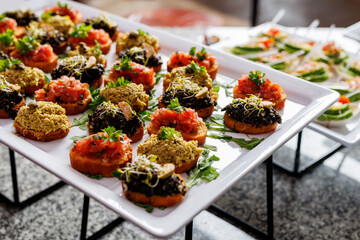 Sandwiches, canapes and vegetable snacks on white plates during buffet breakfast at the hotel.