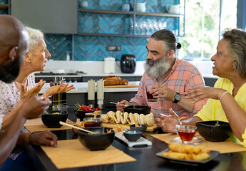 At home, Diverse group of senior friends enjoying meal and conversation in modern kitchen