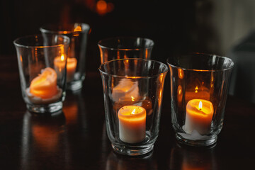 Candles burn in special glasses in a dark interior.