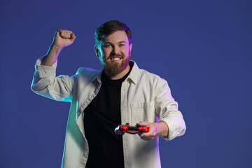 Fototapeta premium Happy man with game controller on dark blue background