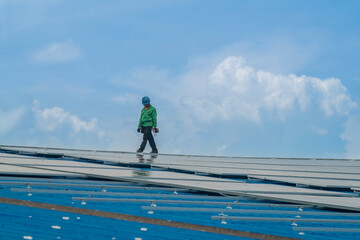 Worker Technicians are working to construct solar panels system on roof. Installing solar photovoltaic panel system. Men technicians walking on roof structure to check photovoltaic solar modules.