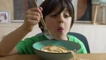 Young boy accidentally spilling spaghetti while eating, capturing a playful and messy moment during mealtime, showcasing the fun and unpredictability of childhood