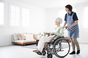 Caregiver pushing wheelchair at home and senior woman's whole body　
For job opportunities and career changes in home nursing and day care (day service) care, with copy space on the left.