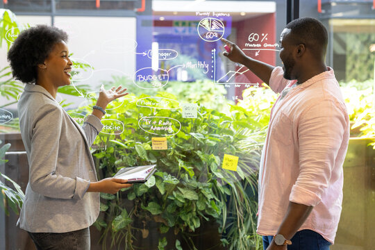 Business people discussing financial data on glass board in modern office