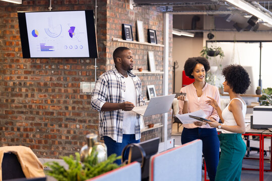 Business team discussing project with laptop and documents in modern office