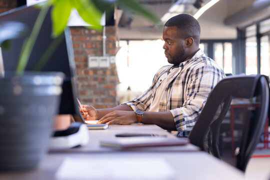 Working at desk, man using laptop in modern casual office environment