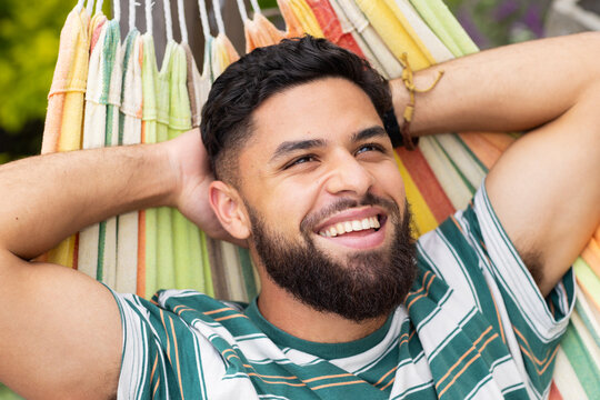 Relaxing in hammock, man smiling and enjoying leisure time outdoors
