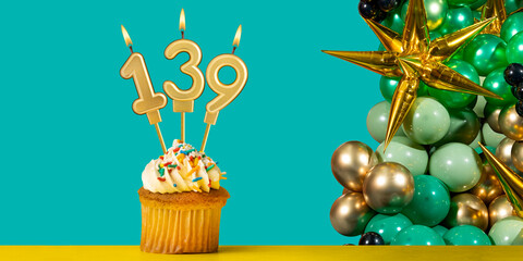 Birthday candle number 139 - Cupcake with decoration on a green background