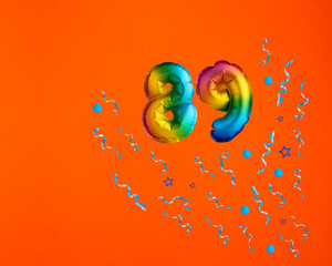 Multicolor balloon number 89 - Confetti explosion on orange background. Birthday card