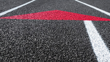 Track and Field Running Lanes. Overhead view of a rubber black running track surface with white lane lines. A red arrow points upwards or forward. Texturized artificial black surface.