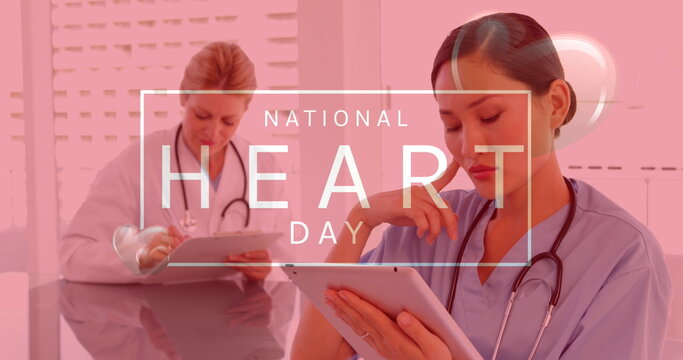 Image of national heart day text over diverse female doctor and nurse using tablets