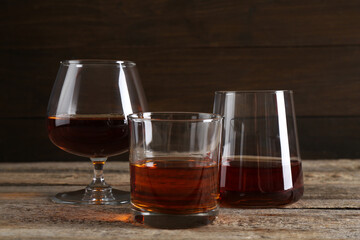 Different delicious liqueurs in glasses on wooden table