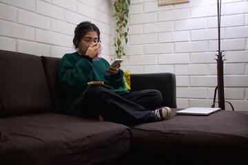 teenage girl sitting on a sofa drinking a cup of tea