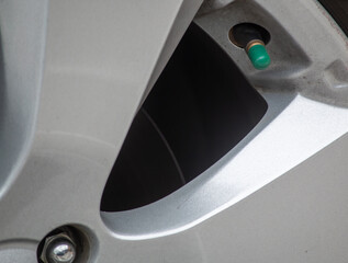 close up of a car wheel valve stem with a green cap.